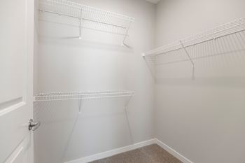 a spacious walk in closet in a 2020 manufactured home with white walls and hanging shelves